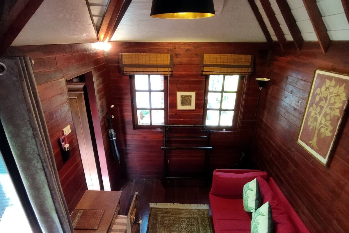 A cozy room with wooden walls, a red sofa, a small table, and a hanging light fixture.