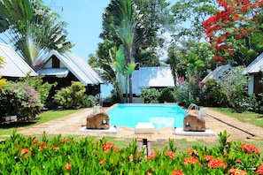 Una piscina al aire libre, sombrillas, sillones reclinables de piscina