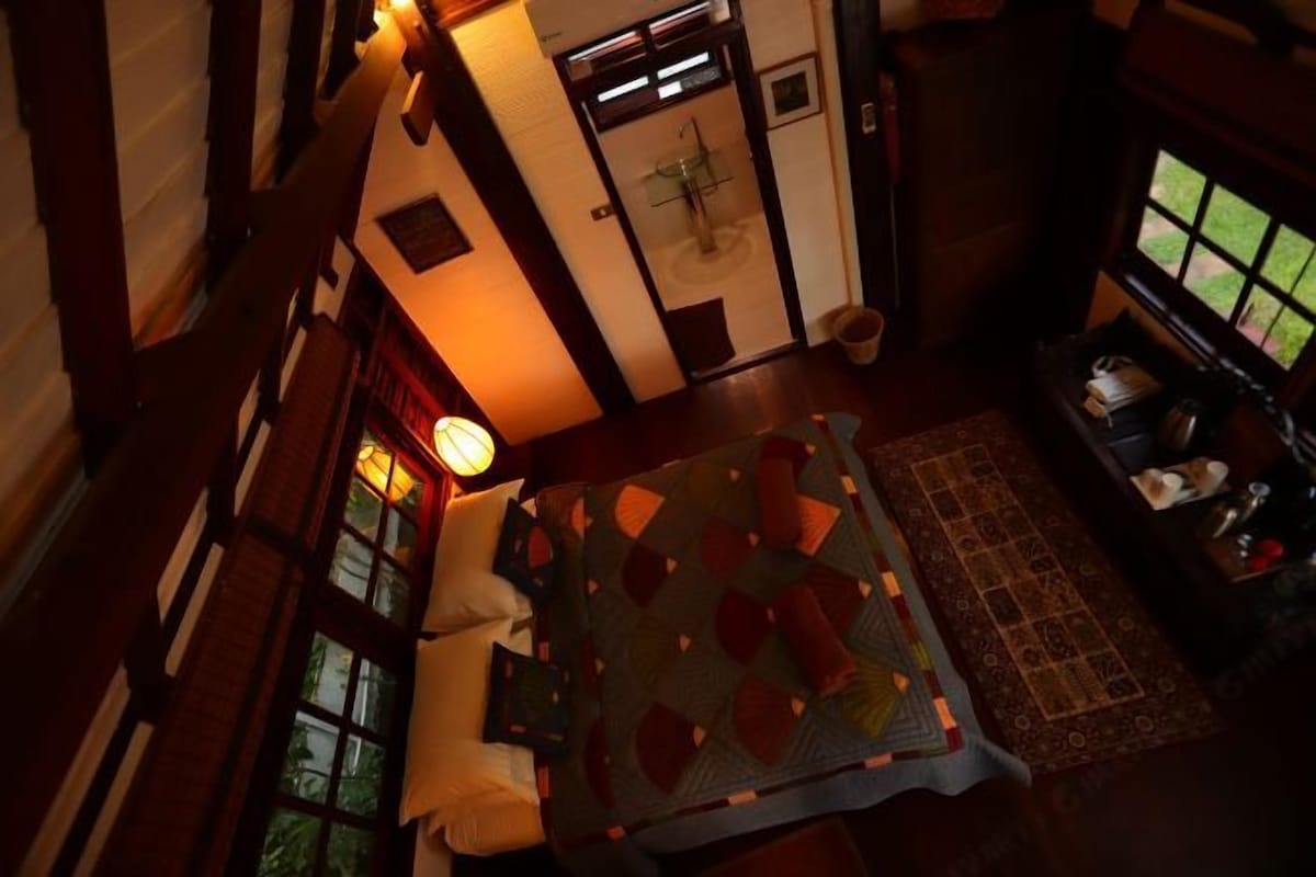 A cozy room with a bed, a small table, a chair, and a window.