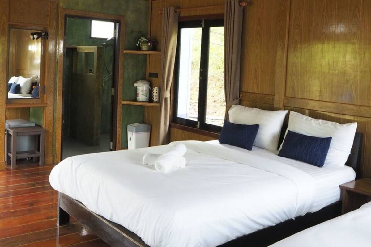 Ein Schlafzimmer mit Holzvertäfelung, einem großen Bett, einem Nachttisch, einer kleinen Kommode und einem Spiegel.