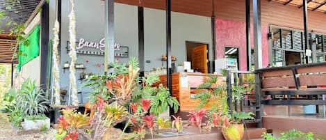 A covered outdoor area with a variety of potted plants and a seating area with wooden benches.