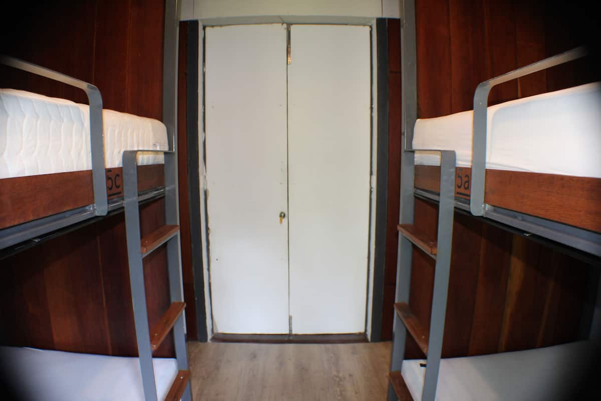 A bunk bed room with a wooden door and metal railings.