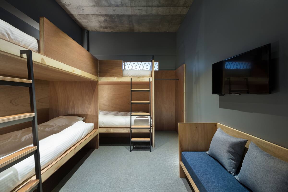 A compact room with bunk beds, a sofa, a TV, and a window with a view.