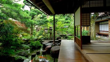A traditional Japanese garden with a koi pond, wooden walkways, and lush greenery.