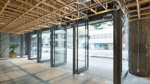 A modern interior with large glass doors, a concrete floor, and exposed wooden beams. - KUMU Kanazawa by The Share Hotels (Kanazawa)