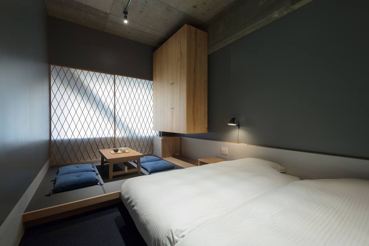 A modern bedroom with a bed, a small table, a bench, and a wardrobe.