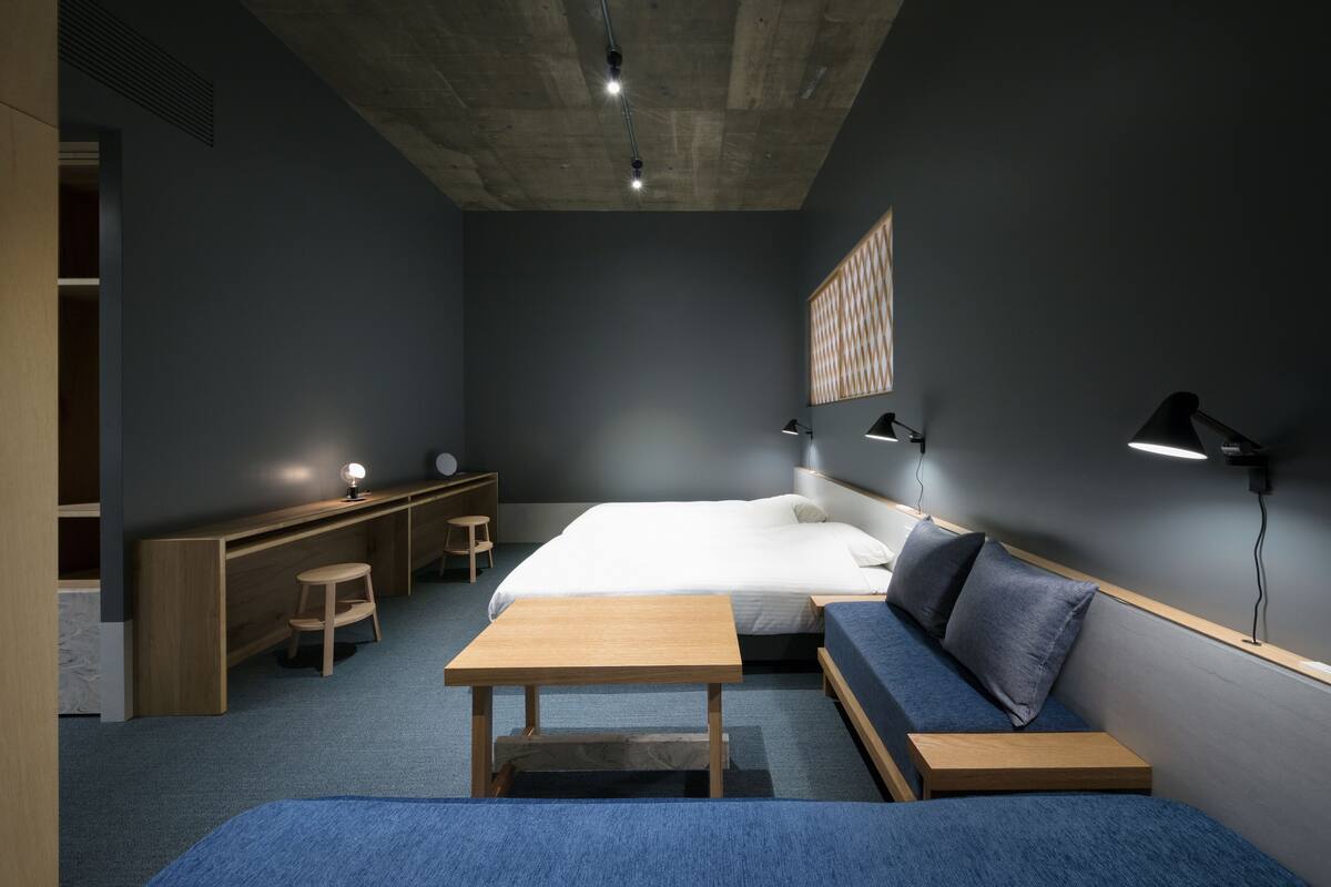 A modern hotel room with a large bed, a sofa, a desk, and a chair.