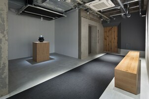 Un interior moderno con un banco de madera, una mesita de madera y un suelo cubierto de alfombra gris.
