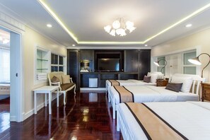 A hotel room with three beds, a desk, a chair, a TV, and a minibar. - The Lek Aree (Bangkok)