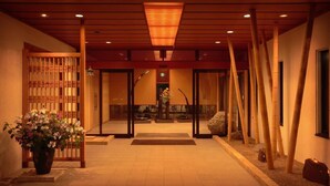 Uma entrada tradicional em estilo japonês, com portão de madeira, planta em vaso e detalhes em bambu.