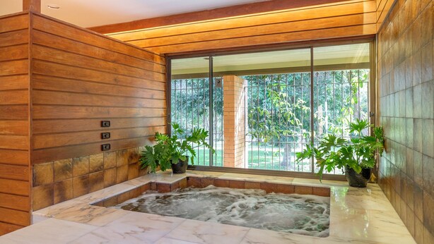 A spa area with a hot tub, wooden walls, and large windows with a view of greenery. - Brookfield Retreat (Brookfield)