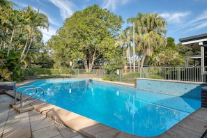 A clear blue swimming pool surrounded by trees and a fenced area. - Brookfield Retreat (Brookfield)