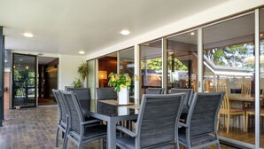 An outdoor dining area with a table and chairs, a potted plant, and a view of the surrounding landscape. - Brookfield Retreat (Brookfield)