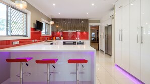 A modern kitchen with a central island, bar stools, and a built-in oven. - Brookfield Retreat (Brookfield)
