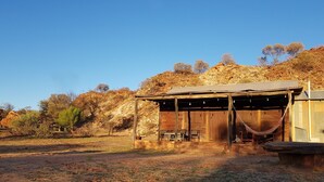 Une structure rustique en bois, dotée d’un porche abrité, d’un hamac et d’un banc.