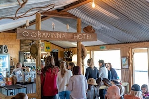 Interior rústico del Hotel Ooraminna, con un letrero de madera, zona de bar y asientos visibles.