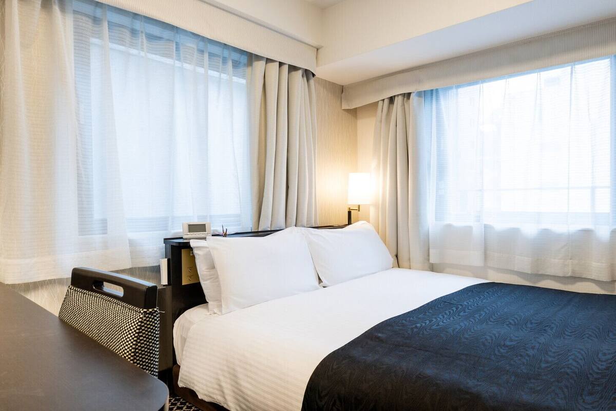 Een hotelkamer met een groot bed, nachtkastje, bureau en een stoel.