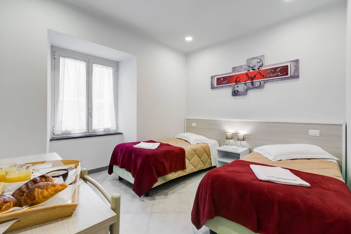 A hotel room with two beds, a breakfast tray with croissants, and a wall art piece.
