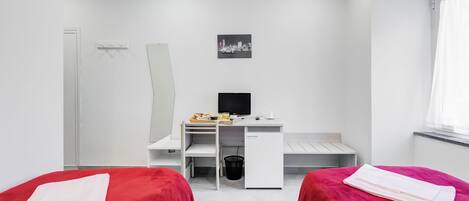 A modern hotel room with two beds, a desk, a chair, a TV, and a window with curtains.