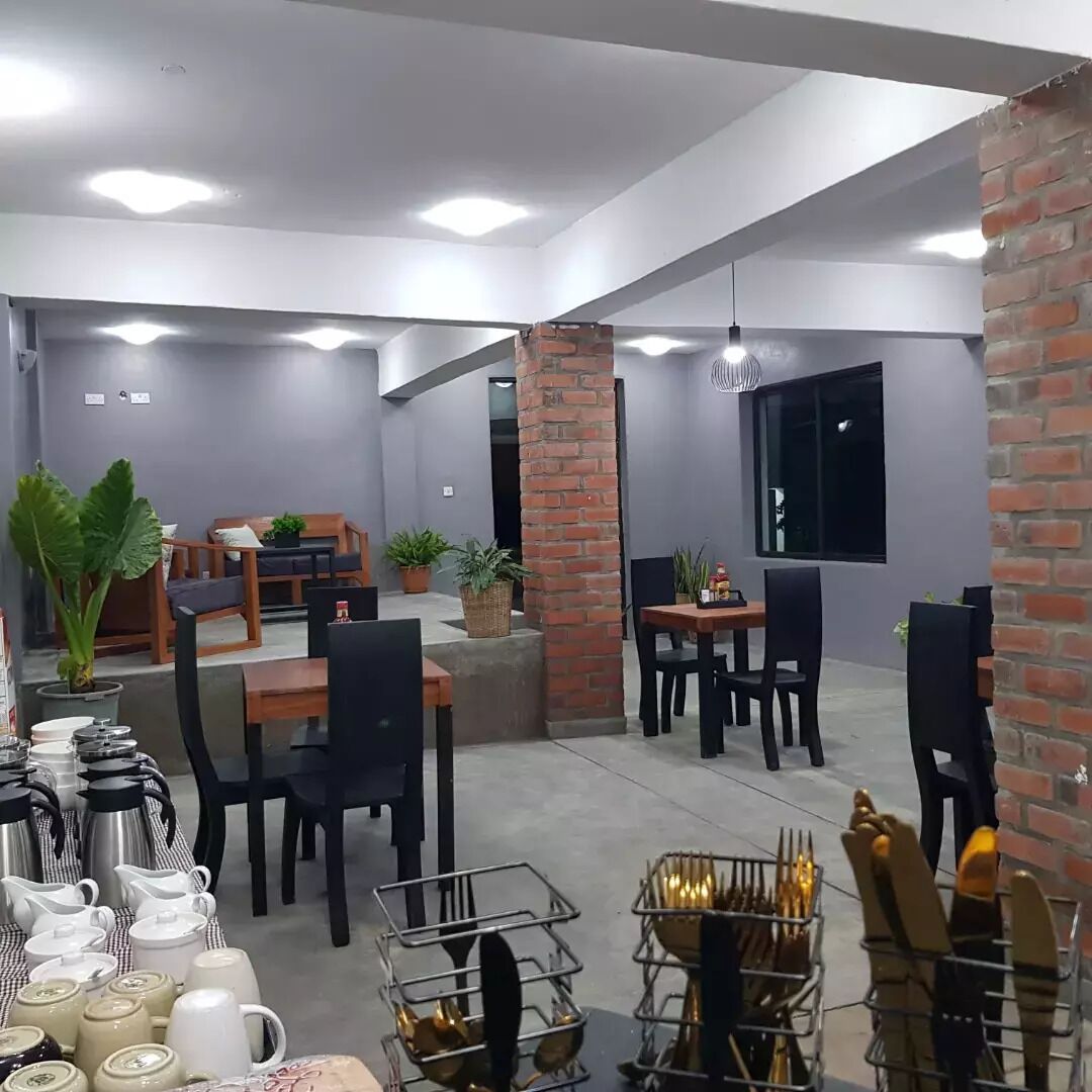 Un comedor moderno con detalles de ladrillo, varias mesas y sillas, y diferentes cubiertos exhibidos sobre las mesas.