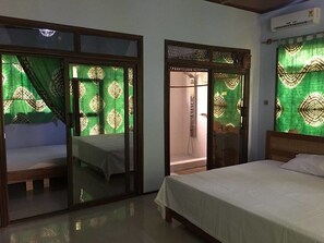 A hotel room with a bed, a small seating area, and a shower.