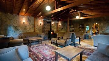 A cozy lounge area with stone walls, wooden beams, and comfortable seating.