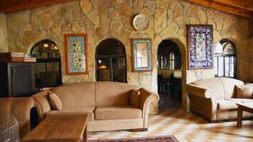 A cozy living room with a stone wall, two sofas, a coffee table, and a fireplace.