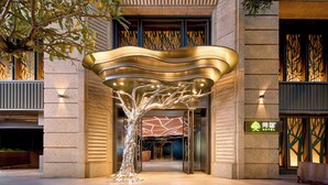 A modern hotel entrance with a unique tree-shaped light installation and a visible sign for the hotel. - arTree hotel (Taipei)