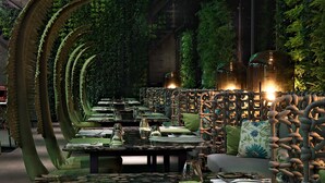 A restaurant with a unique curved wall design, tables set with glassware, and a cozy seating area with cushions. - arTree hotel (Taipei)
