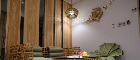 A modern living room with a wicker sofa, a coffee table, and a large green plant.