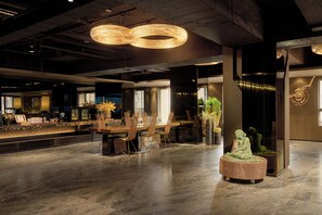 A spacious lobby with a long reception desk, modern chairs, and a central seating area with a sculpture. - arTree hotel (Taipei)