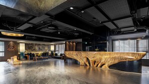 A modern reception area with a unique wooden reception desk, seating area with sofas, and a large window providing natural light. - arTree hotel (Taipei)