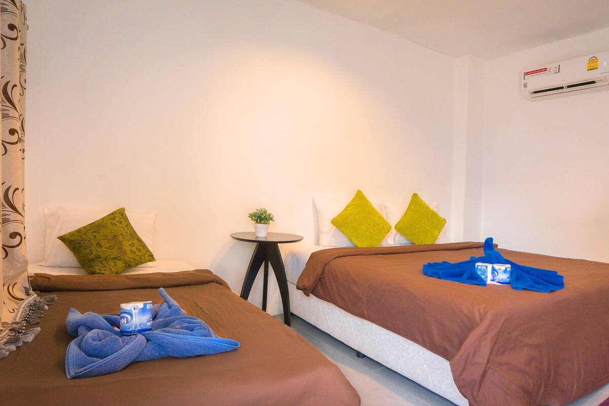 Een hotelkamer met een bed, een bank, een bureau met een computer en een airconditioner.