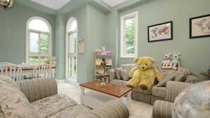 A cozy living room with striped sofas, a large teddy bear, and a bookshelf. - Dancing Butterfly Slide Family Inn (Dongshan)