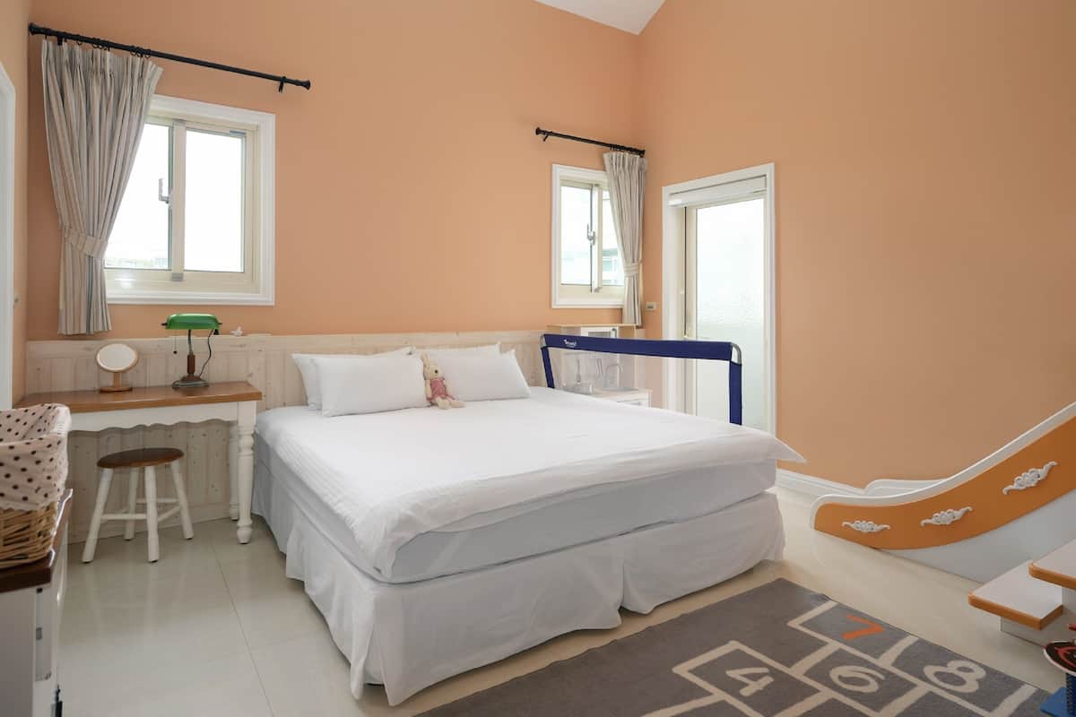 A bedroom with a bed, a desk, a chair, and a window.