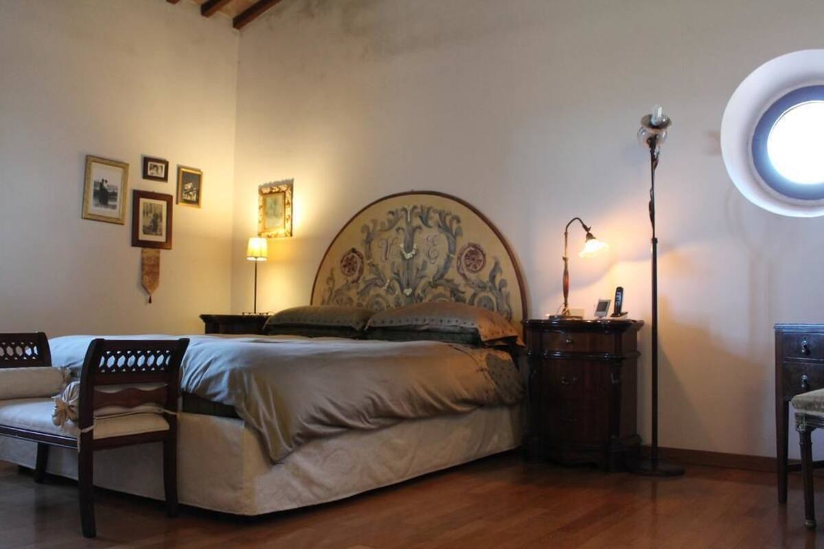 A bedroom with a bed, a chair, a nightstand, and a lamp.