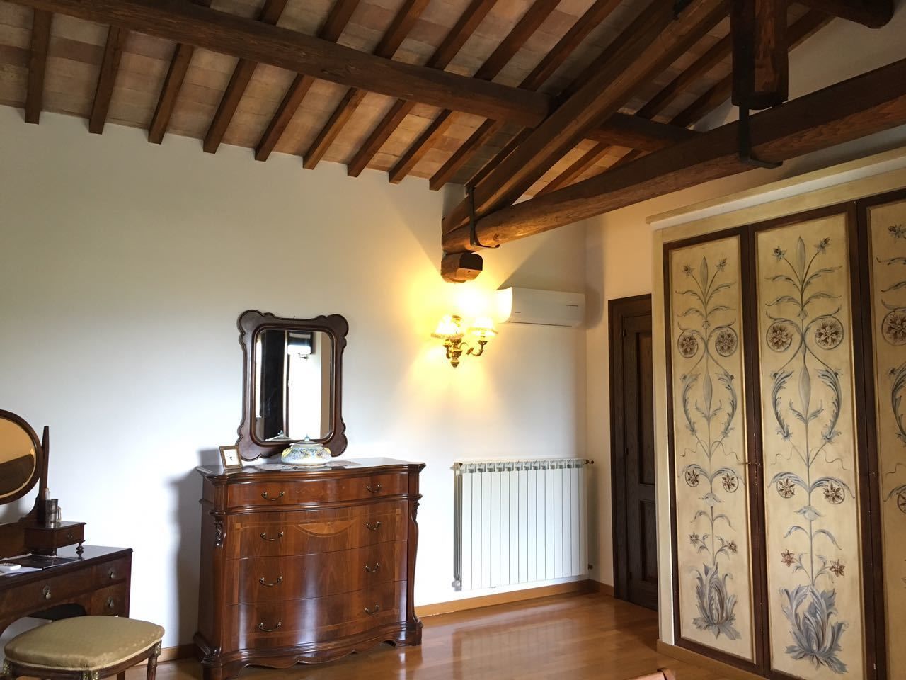 Una habitación con techo de madera, un aparador con espejo, una lámpara de pared y un radiador.