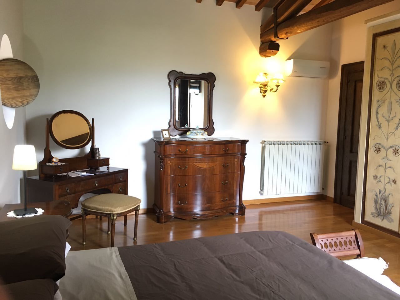 Een slaapkamer met een bed, een dressoir, een spiegel, een lamp en een radiator.