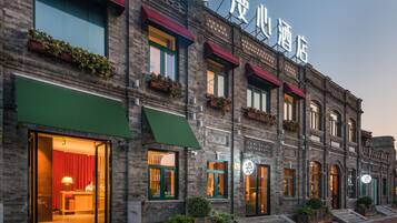 A hotel with a brick facade, green awnings, and a sign with Chinese characters.