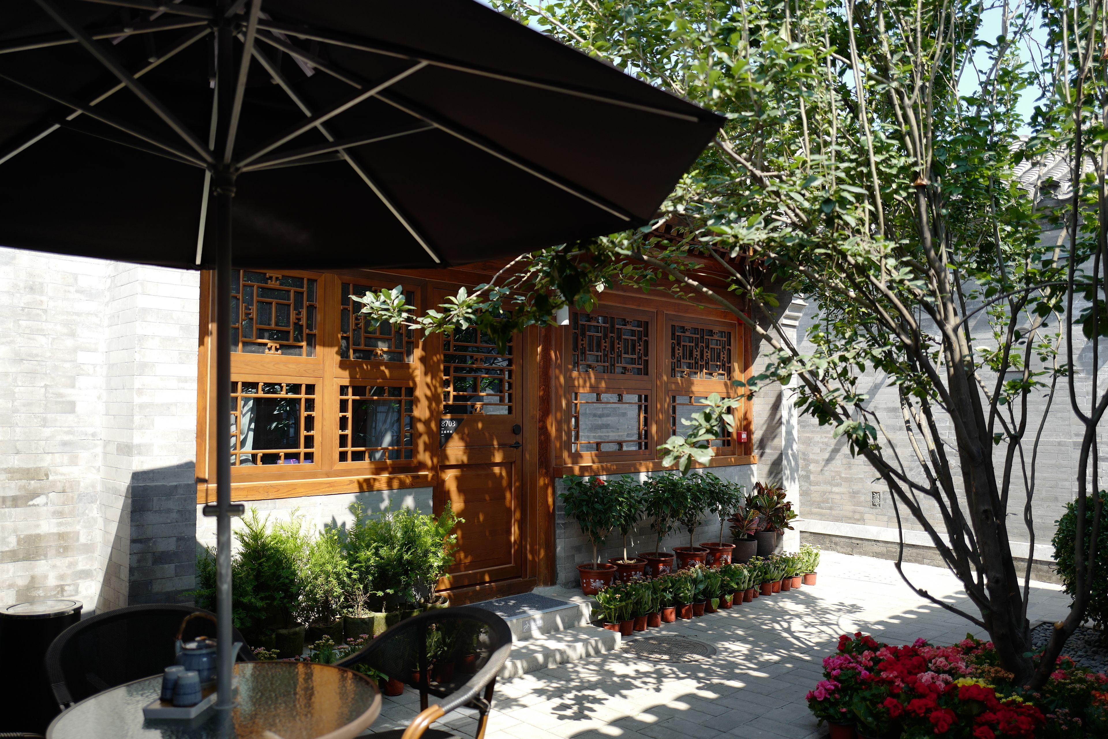 A traditional building with wooden doors and windows, surrounded by potted plants and a small table with chairs.