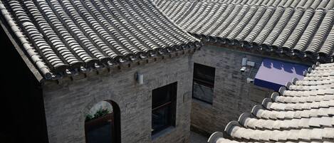 A traditional building with a tiled roof and brick walls, featuring a window and a small door.
