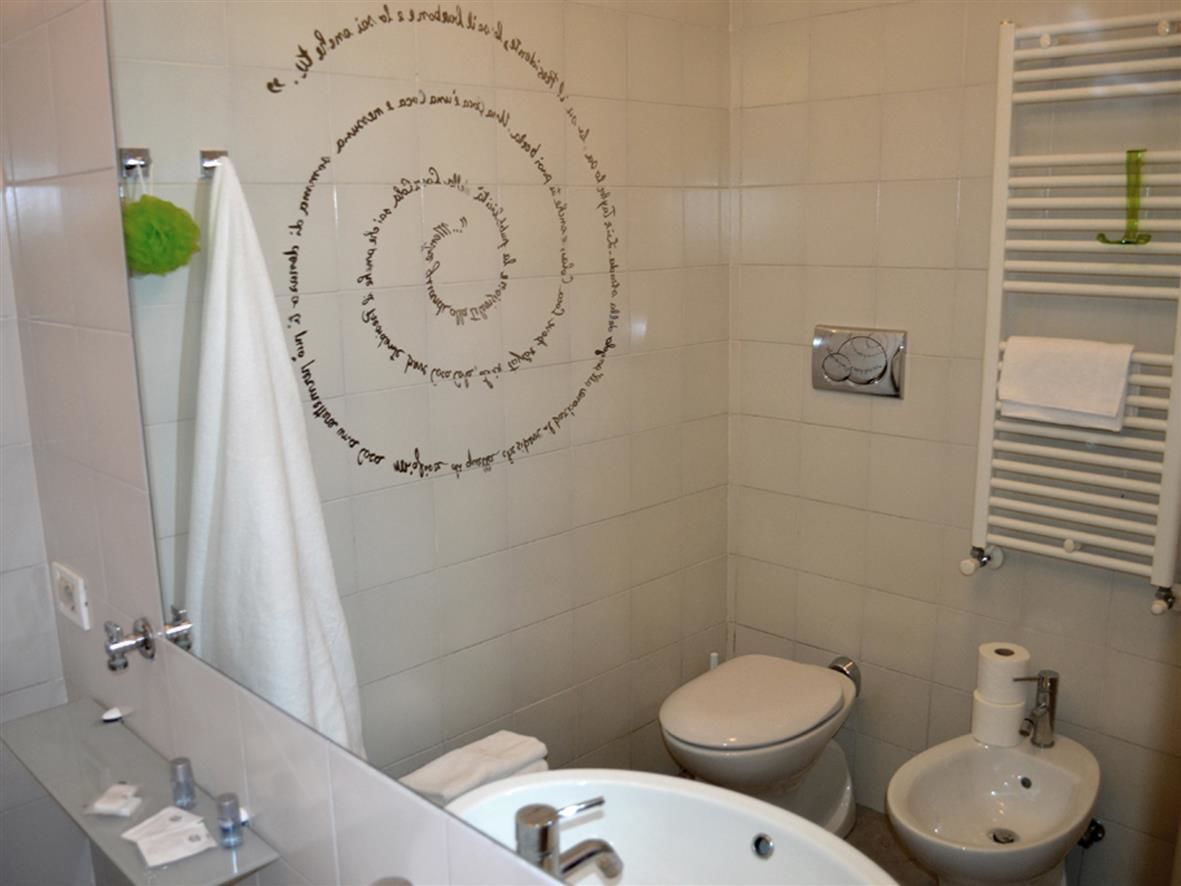 A bathroom with a toilet, bidet, sink, and a towel rack.
