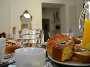 Un desayuno con un croissant, un vaso de agua y una taza sobre una mesa.