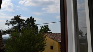 Un bâtiment jaune avec un toit en tuiles, entouré d’arbres et sous un ciel dégagé.