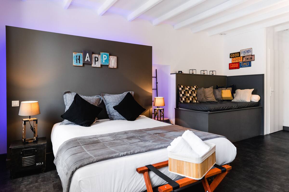Una habitación de hotel moderna con cama, mesitas de noche, sofá y decoración mural.