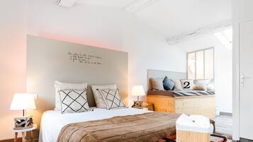 Ein modernes Schlafzimmer mit einem großen Bett, zwei Nachttischlampen, einem Holzkopfende und einer Wand mit einem motivierenden Zitat.