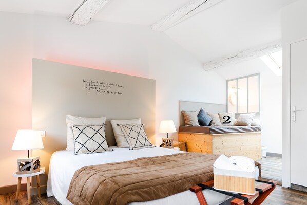Un dormitorio moderno con una cama grande, dos lámparas de noche, un cabecero de madera y una pared con una cita motivacional.