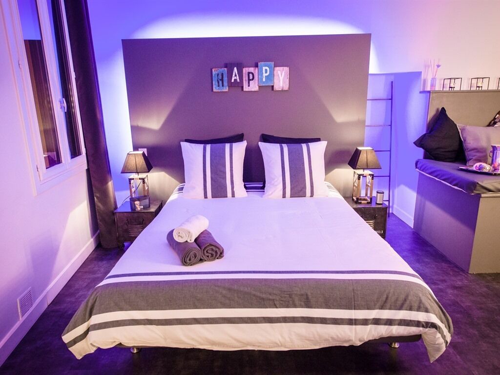 Et hotelværelse med en seng, to sengeborde, et skrivebord og et skilt med teksten 'HAPPY' på væggen.