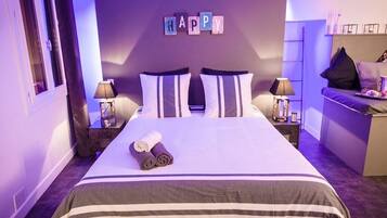 Et hotelværelse med en seng, to sengeborde, et skrivebord og et skilt med teksten 'HAPPY' på væggen.