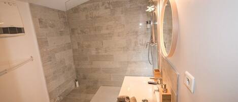 A modern bathroom with a shower, a vanity with a mirror, and a towel on the counter.
